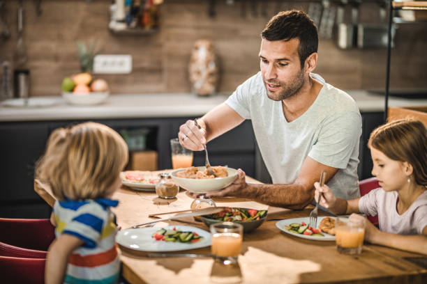 istock Young single father having lunch with his kids at dining table. 1330855250