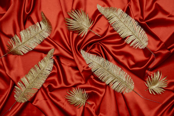 istock Decorative golden leaves on red textile backdrop 1330857606