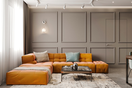 Modern apartment living room interior with large sofa, in front of a blank wall with classic mouldings. Copy space render