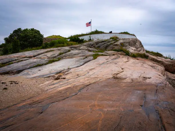 Photo of Red rock hill on the Fort Phoenix in New Bedford, Massachusetts. American flag waving on the hilltop.