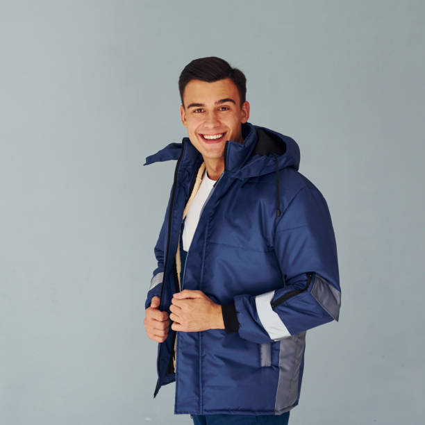 istock In warm jacket. Male worker in blue uniform standing inside of studio against white background 1330859181
