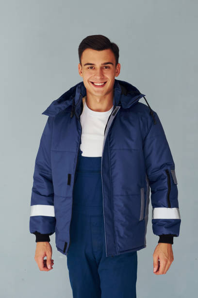 istock In warm jacket. Male worker in blue uniform standing inside of studio against white background 1330859229
