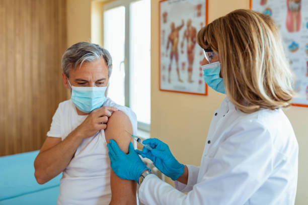 medical worker vaccinates a mature man in the arm in a medical office.medicine and healthcare concept.vaccination against coronavirus. - injecting flu virus cold and flu doctors office imagens e fotografias de stock