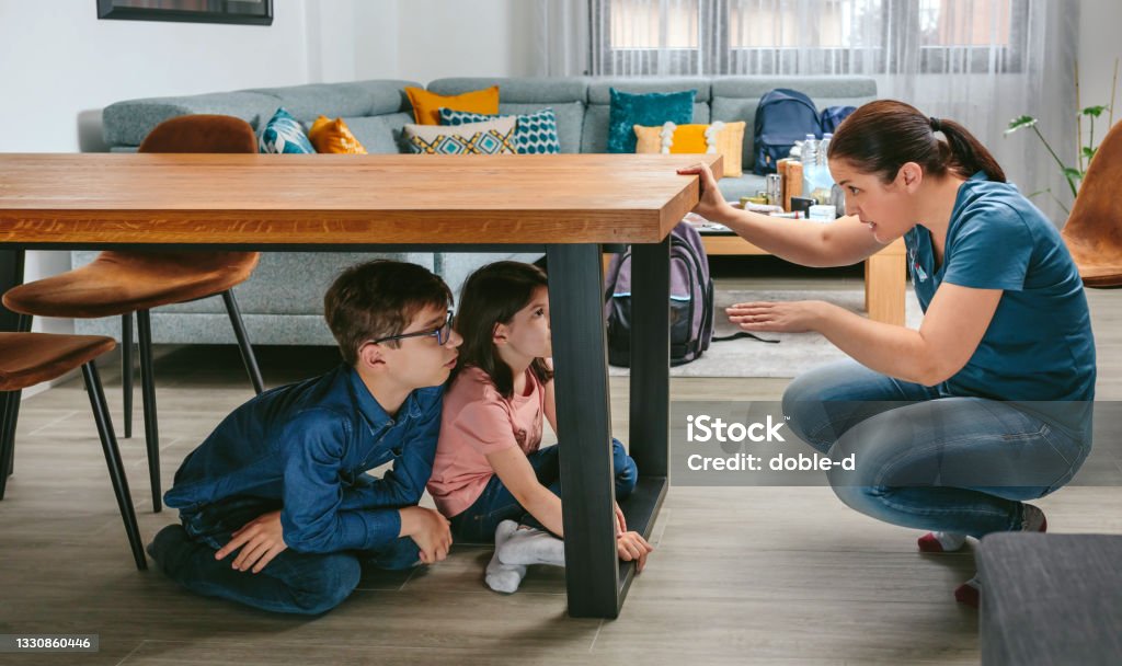 Mother explaining to her children how to protect themselves in an earthquake - Royalty-free Aardbeving Stockfoto