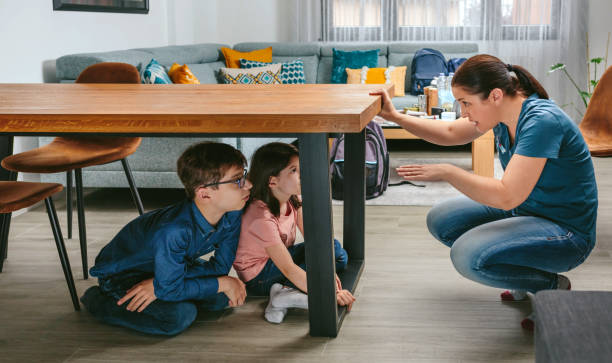 Mother explaining to her children how to protect themselves in an earthquake stock photo