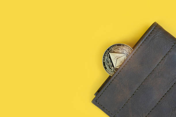 Ethereum in a wallet on yellow background with copy space Ethereum or Eth crypto currency coin in a brown leather wallet on yellow background with copy space. Banner with space for text. ethereum stock pictures, royalty-free photos & images