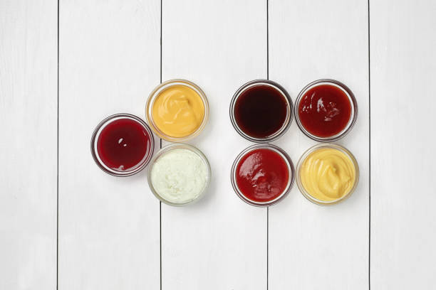 istock Glass bowls with dipping sauces on white wooden surface 1330863345