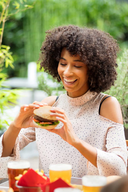 istock Vivacious happy young black woman eating a hamburger 1330866321