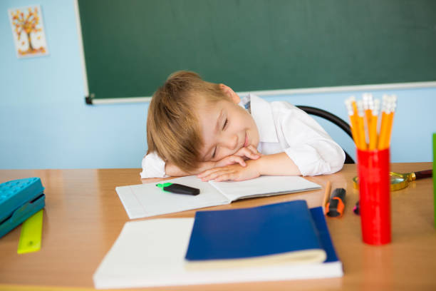 istock Tired child sleeping while studying in the primary school classroom. Difficult school assignments. Overwork 1330867796