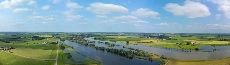 Overflowing floodplains caused by high water level of the river IJssel between Zwolle and Kampen on July 20 2021. Wide panorama aerial drone point of view over the river and overflown fields after heavy rainfall upstream in Germany.