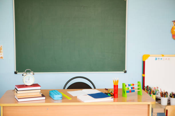 istock Teacher's desk with writing materials, a book and a blank for text or a background for a school theme. Copy space 1330868189