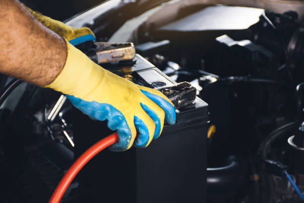 istock Technician clamps charger cables to the car battery 1330868428