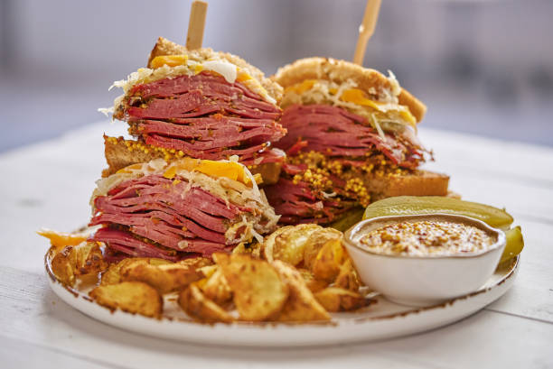 Reuben sandwich. Classic traditional American sandwich. Pastrami and corned beef on grilled bread Reuben sandwich. Classic traditional American sandwich. Pastrami and corned beef on grilled bread, melted cheddar cheese, sauerkraut. Served potato wedges. reuben sandwich stock pictures, royalty-free photos & images
