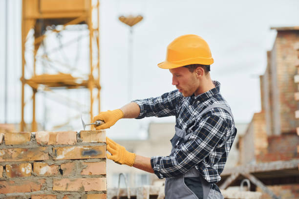 istock Laying bricks. Construction worker in uniform and safety equipment have job on building 1330871377