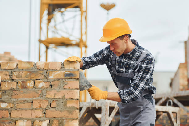 istock Laying bricks. Construction worker in uniform and safety equipment have job on building 1330871378
