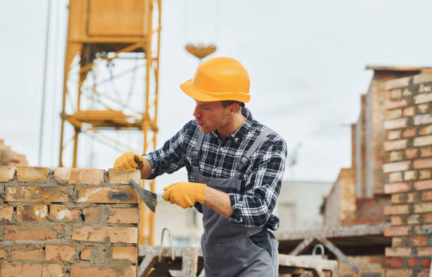 istock Laying bricks. Construction worker in uniform and safety equipment have job on building 1330871417