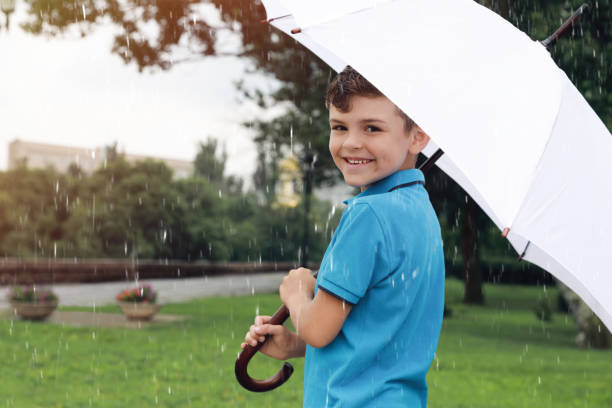 istock Little boy with umbrella walking under rain in park 1330873127