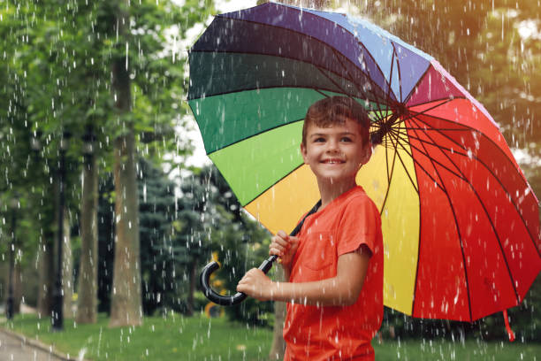 istock Little boy with umbrella walking under rain in park 1330873137
