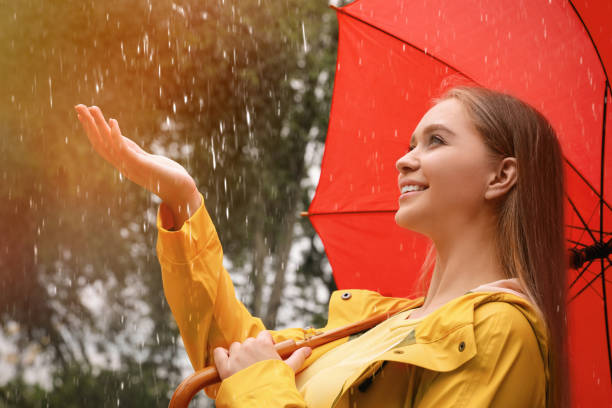 istock Young woman with umbrella walking under rain in park 1330873266