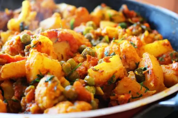 Preparation of Potatoes & Cauliflower (Aloo Gobi) a popular vegan Indian recipe that is served as a main course meal.