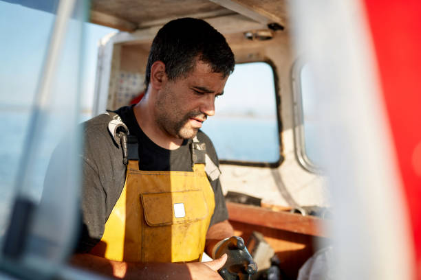 istock Fisherman Standing in Pilothouse Removing Work Gloves 1330878488