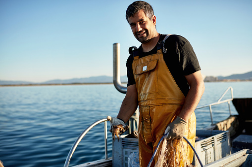 Retrato sincero de pescador sosteniendo redes y sepias photo