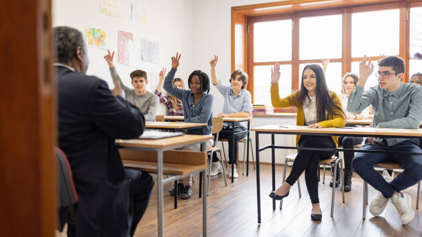 istock High school students raising hands to answer teacher's question 1330878677