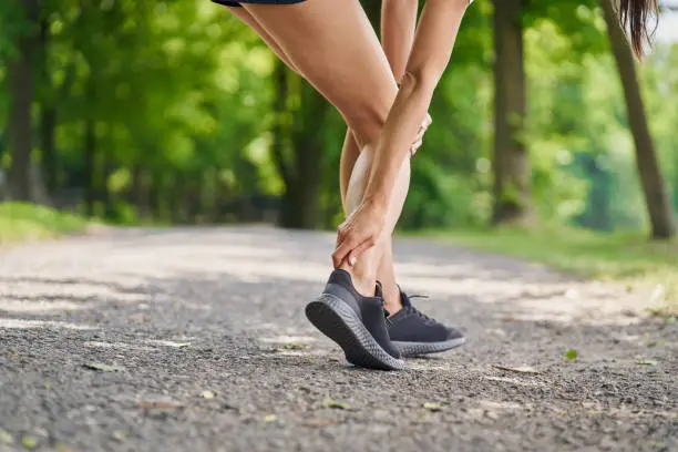 Achilles tendonitis. Female runner holding injured achilles