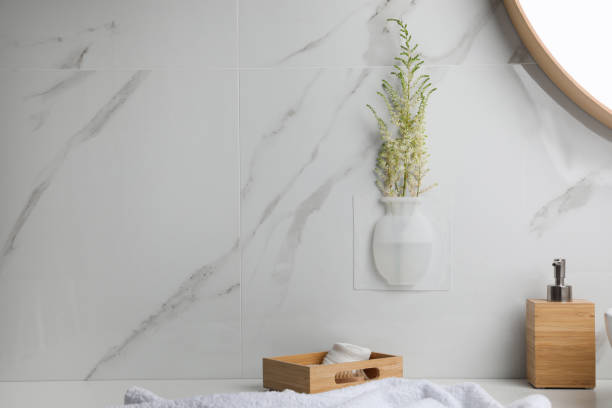istock Silicone vase with flowers on white marble wall in stylish bathroom. Space for text 1330882627