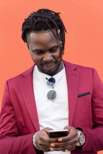 istock african man in suit typing a message on his phone 1330882783