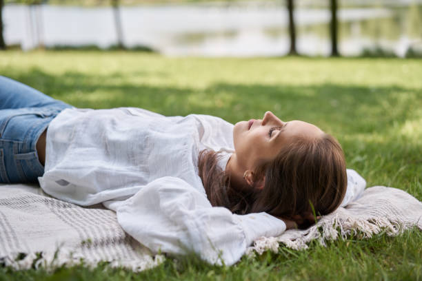 Relaxed woman lying sleeping with closed eyes on blanket in park