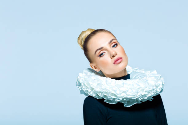 Portrait of woman wearing neck ruff Woman wearing black turtleneck and white neck ruff looking at camera. Studio shot on blue background. neck ruff stock pictures, royalty-free photos & images