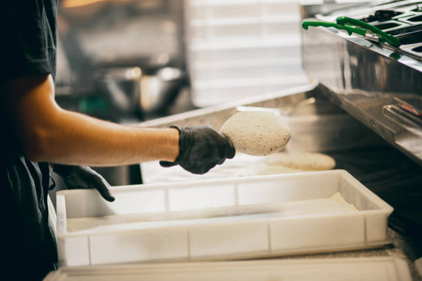 istock Young chef preparing bread, pastries, kneading the dough on the table in restaurant kitchen. Side view. 1330888936