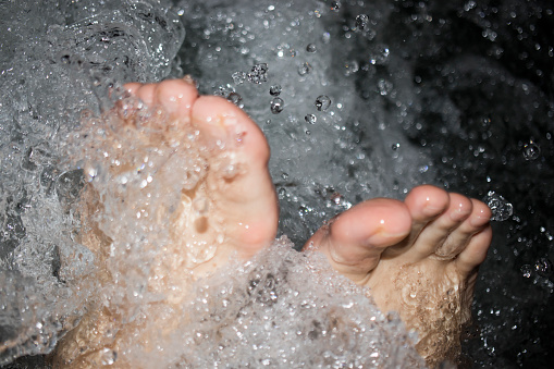 white human foot among bubbles of water. playing with water and vacation.