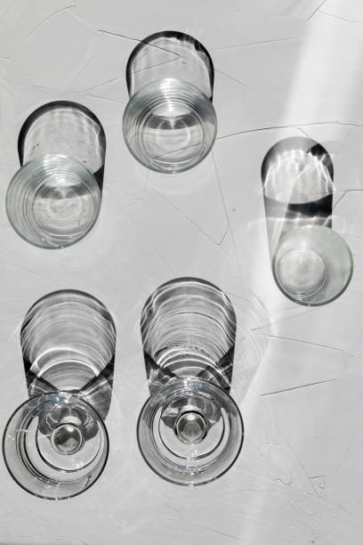 istock Glass on a grey concrete table with sunbeams and reflections 1330890476