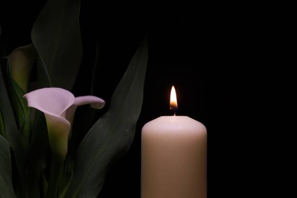 istock Candle burning flame in the darkness and arum lilies 1330890538
