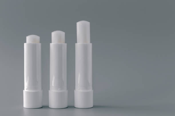 istock Side view of white lip balm tubes on gray background. 1330896910