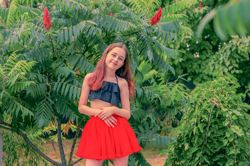 Young girl in a red skirt. Teenager girl summer portrait outdoor.