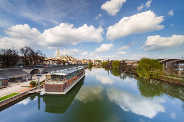 Wide sunset view of the Isle river with a barge or houseboat and the Saint Front cathedral in the background from the bridge Saint George. Perigueux, Dordogne Department, Nouvelle Aquitaine region. France.