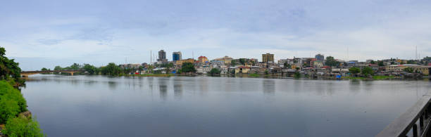 Monrovia, Liberia: urban skyline and the Mesurado River - wide angle view with Monrovia's central business district, buildings along Water Street and on the skyline government buildings on Broad Street - Providence Island on the left. Monrovia is located on the southern branch of the mouth of the Saint Paul River in the Atlantic, in an area that was bought from Sierra Leone, near Cape Mesurado. About 40 percent of the official urban area is taken up by the marshy mangrove forest of the Mesurado River.
