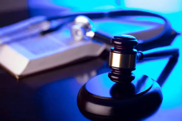 Gavel, legal code and stethoscope on the glass table. Blue light.