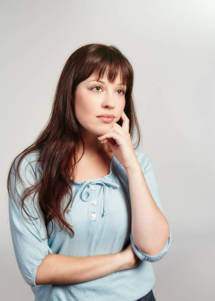 istock Beautiful young woman deep in thought, hand on her chin 1330901447