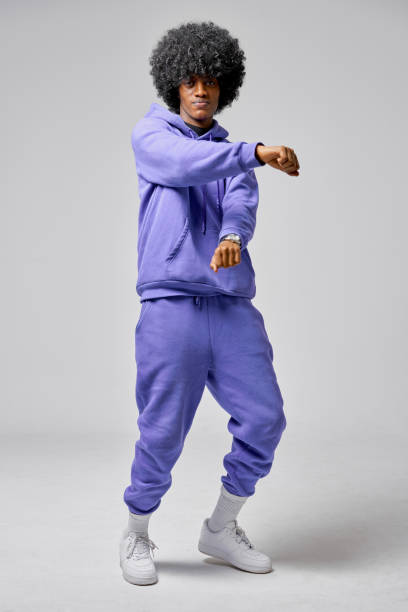 Young black man in set of purple tracksuit Young black man dancing in blue set of tracksuit isolated on gray background tracksuit stock pictures, royalty-free photos & images