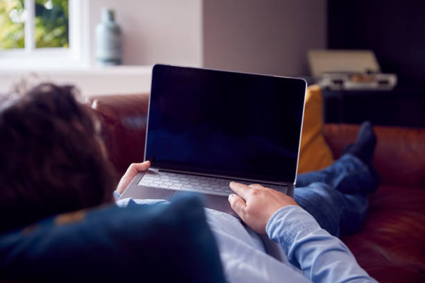 istock Relaxed Man Lying On Sofa At Home Looking At Laptop 1330907406