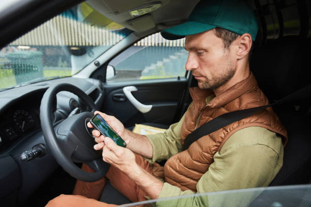 conductor que usa la aplicación de navegación en el automóvil - driving text messaging telephone mobile phone fotografías e imágenes de stock