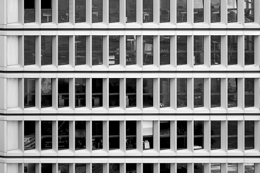 Monotonous facade of office tower with large window front in concrete construction, black and white