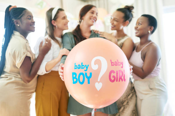 foto de un grupo de mujeres a punto de hacer estallar un globo para una revelación de género durante un baby shower - baby shower women home interior indoors fotografías e imágenes de stock