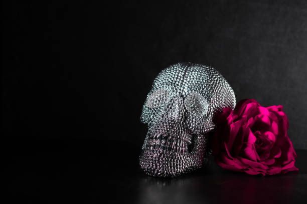 Shiny sparkling bright skull candy for Día de Muertos decorated with a purple rose. Empty space for text on the side.  Party invitation for Halloween.