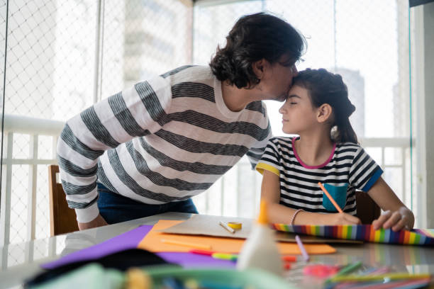 istock Father kissing daughter while she is studying at home 1330915621