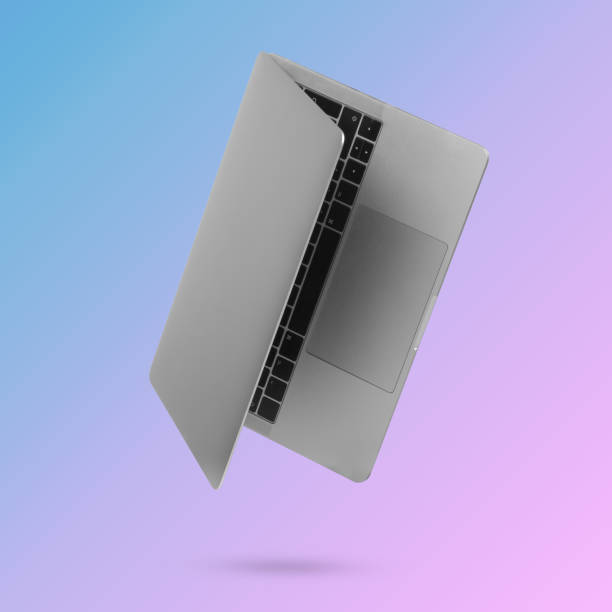 istock Laptop computer levitating in the air on a trendy background illuminated by a blue and pink color gradient. 1330918435